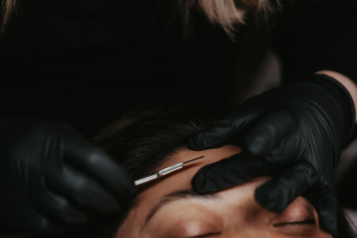 experienced Esthetician in Appleton Wi gently moving a dermaplane tool on her client's skin during her facial.