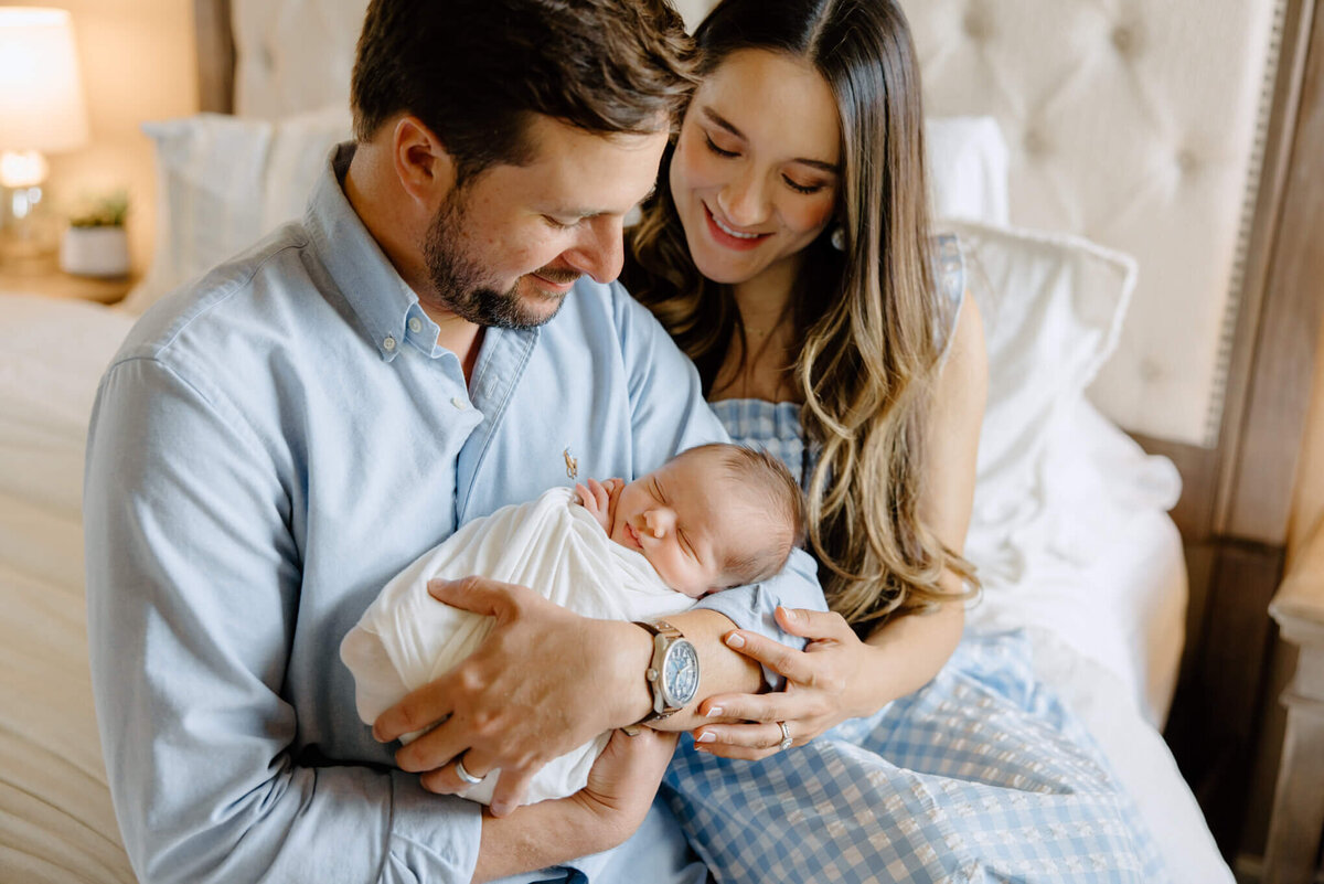 couple holding and looking at newborn son during in home lifestyle newborn session