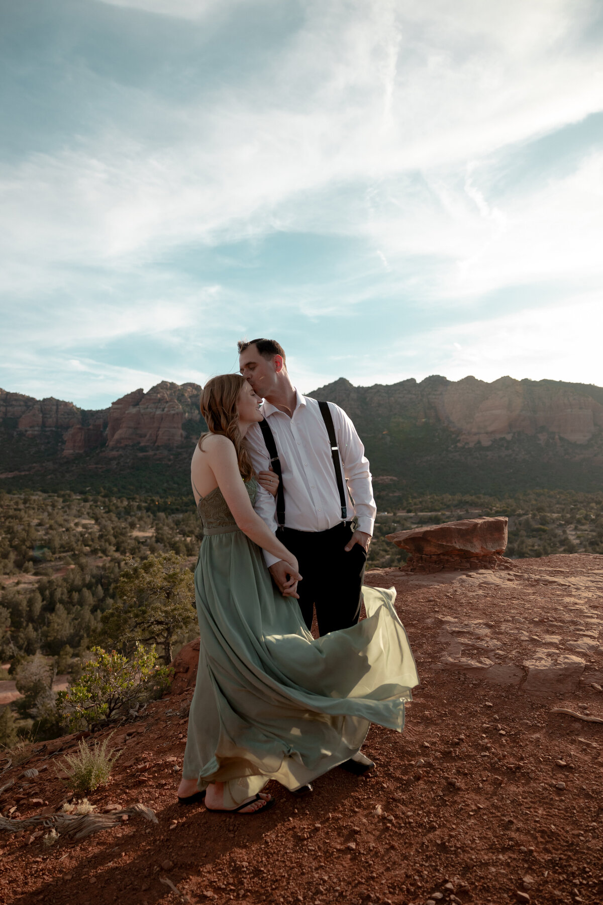 Couple standing against red rock backdrop during Sedona engagement session