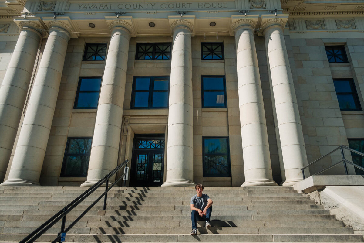 Boy poses at Yavapai County Courthouse in Prescott senior photography session