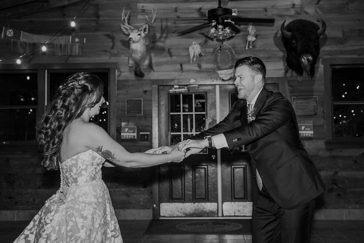 A bride and groom share the first dance of their wedding in a summer camp lodge. 
