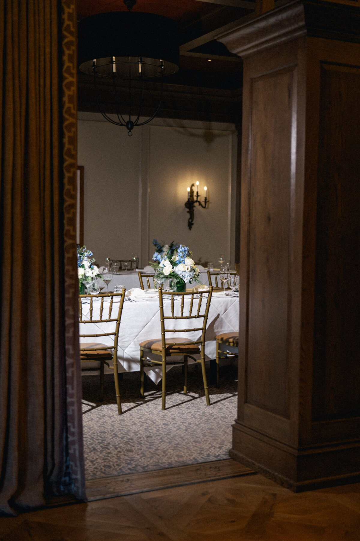 Intimate wedding dinner setup with elegant floral centerpieces and gold chairs