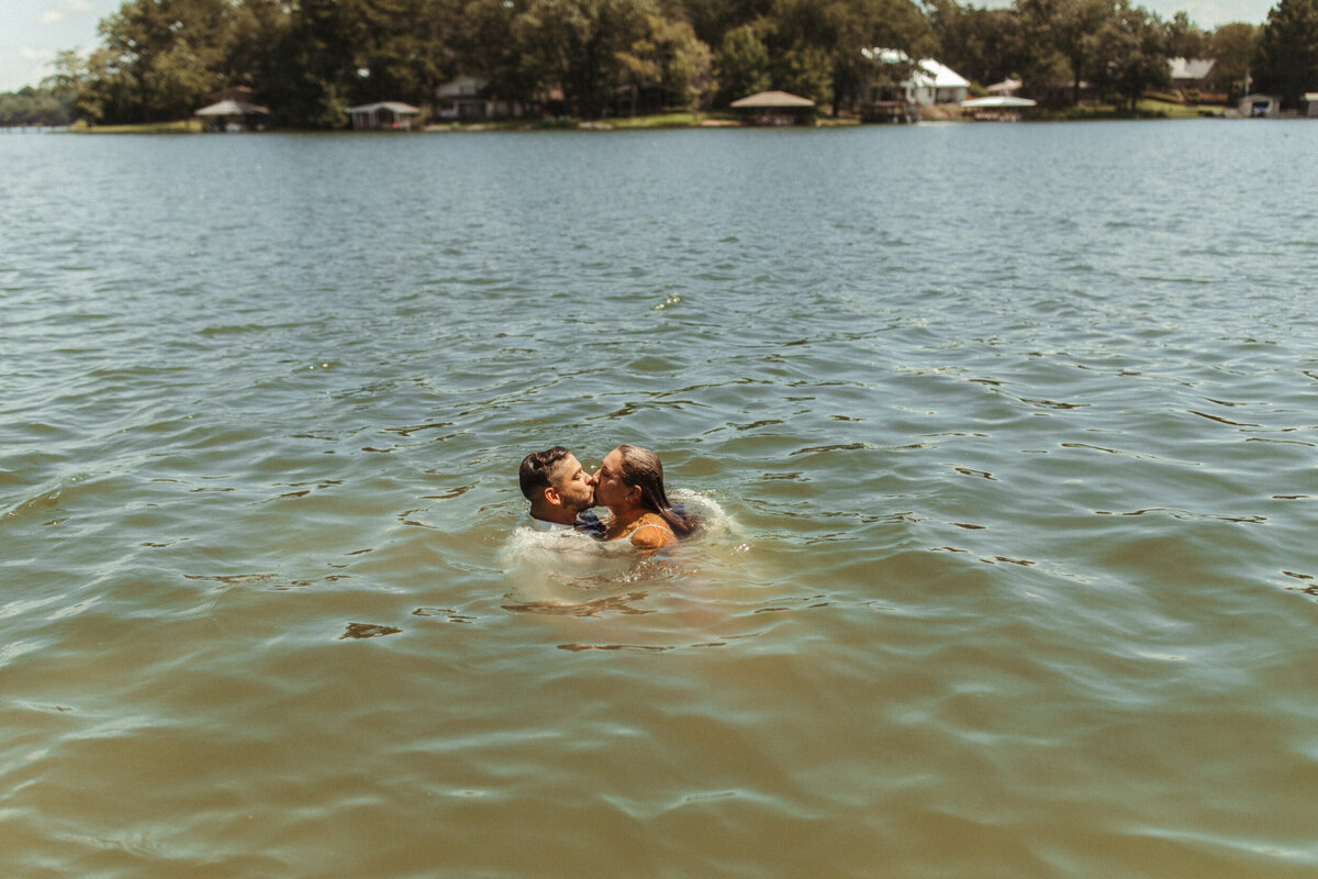 Bride and groom swimming in lake in their wedding attire