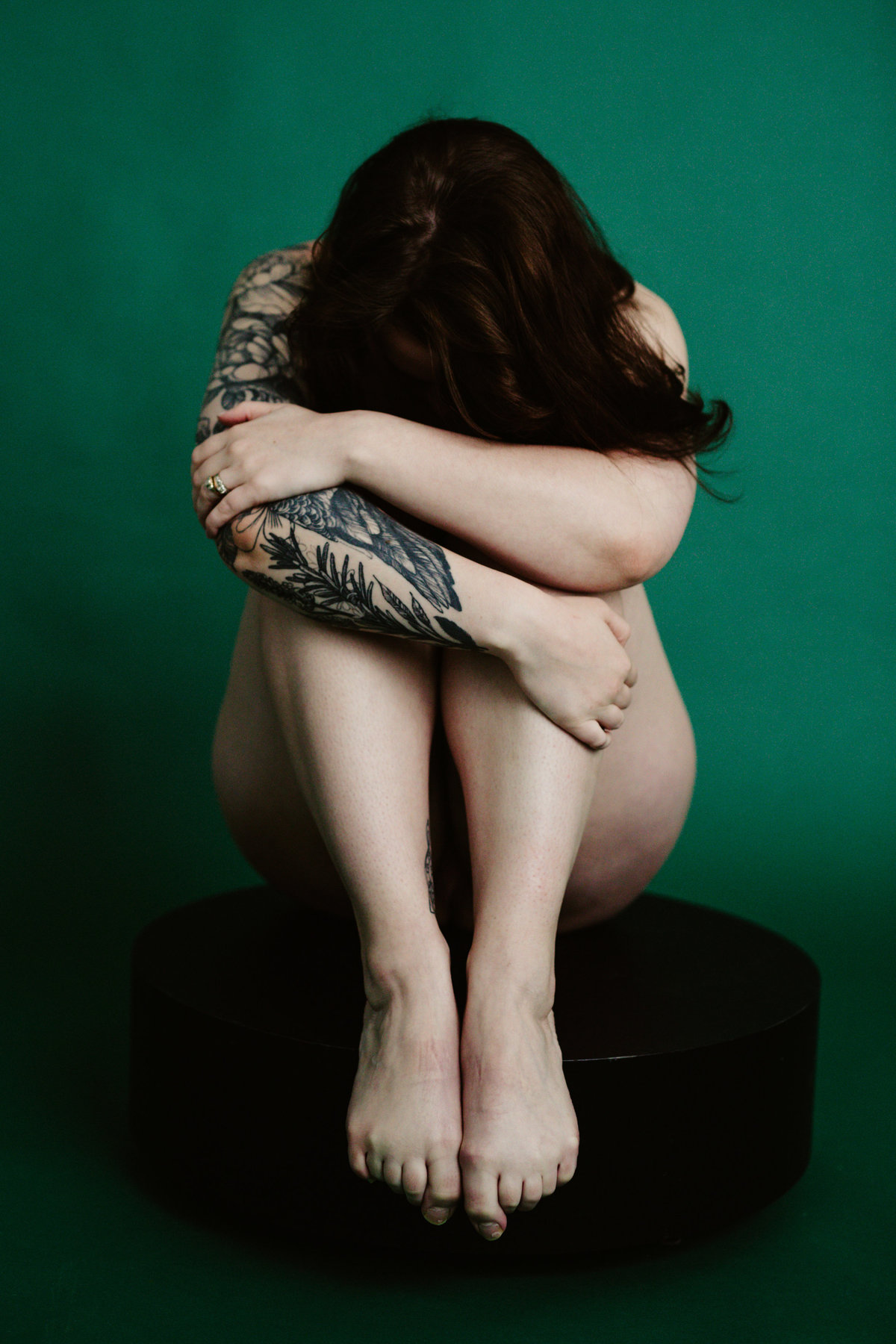 tattood woman folded over her body on green background