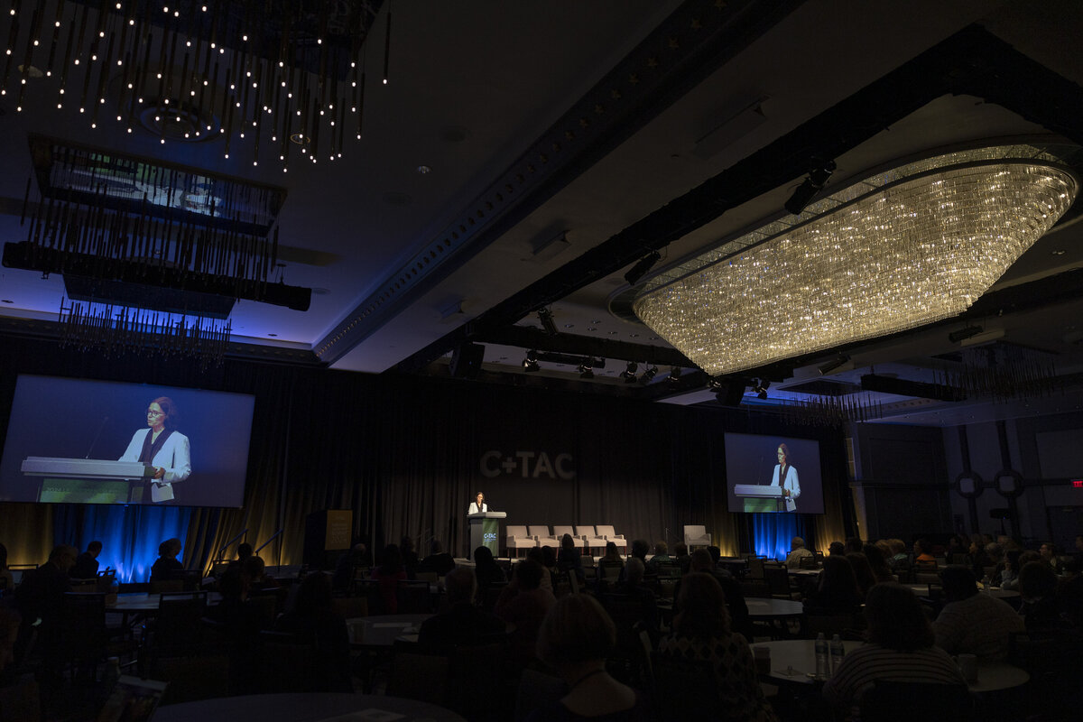 A person speaks on a stage at an event.