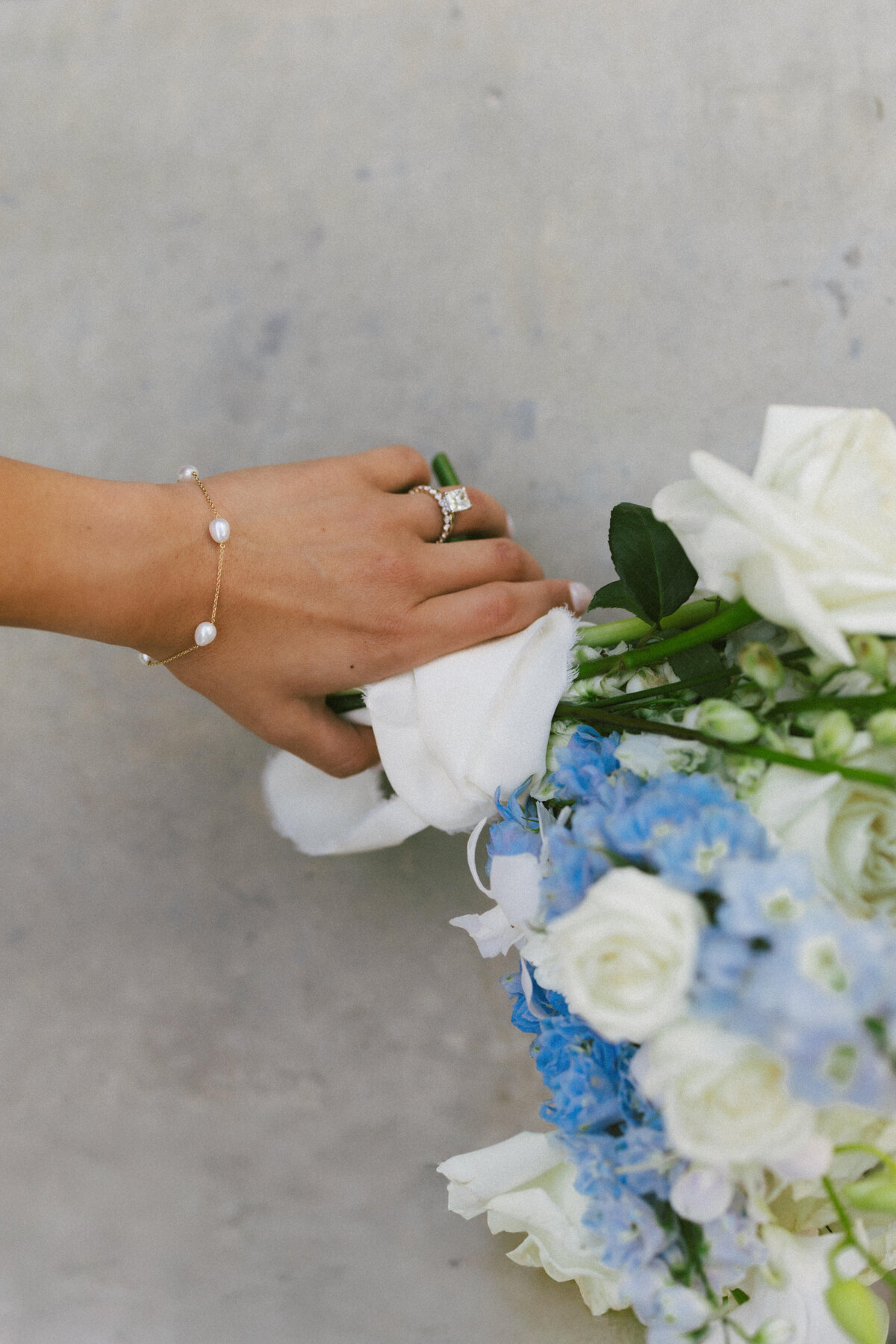 bride holds her flower bouquet and shows off wedding rings