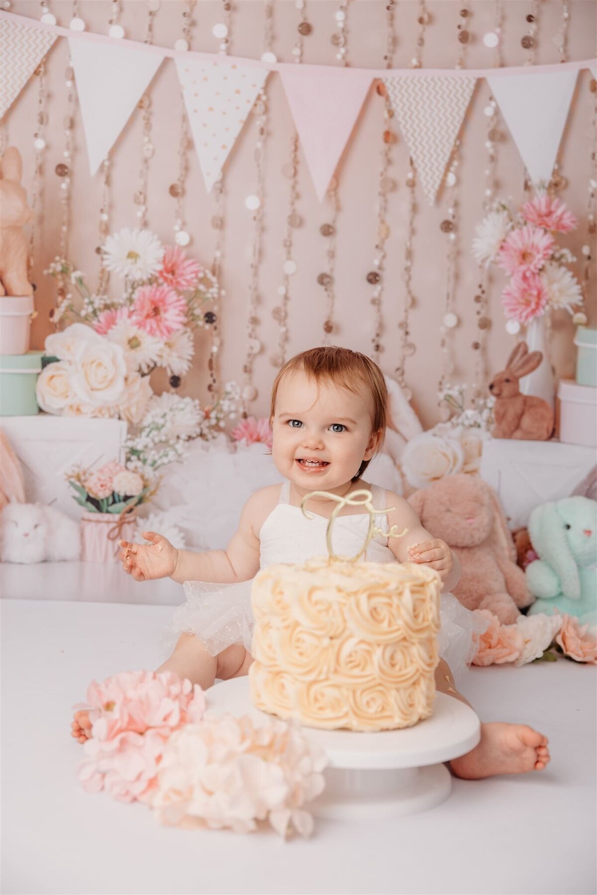 Olivia smiling at the camera during her first birthday cake smash photoshoot in auckland