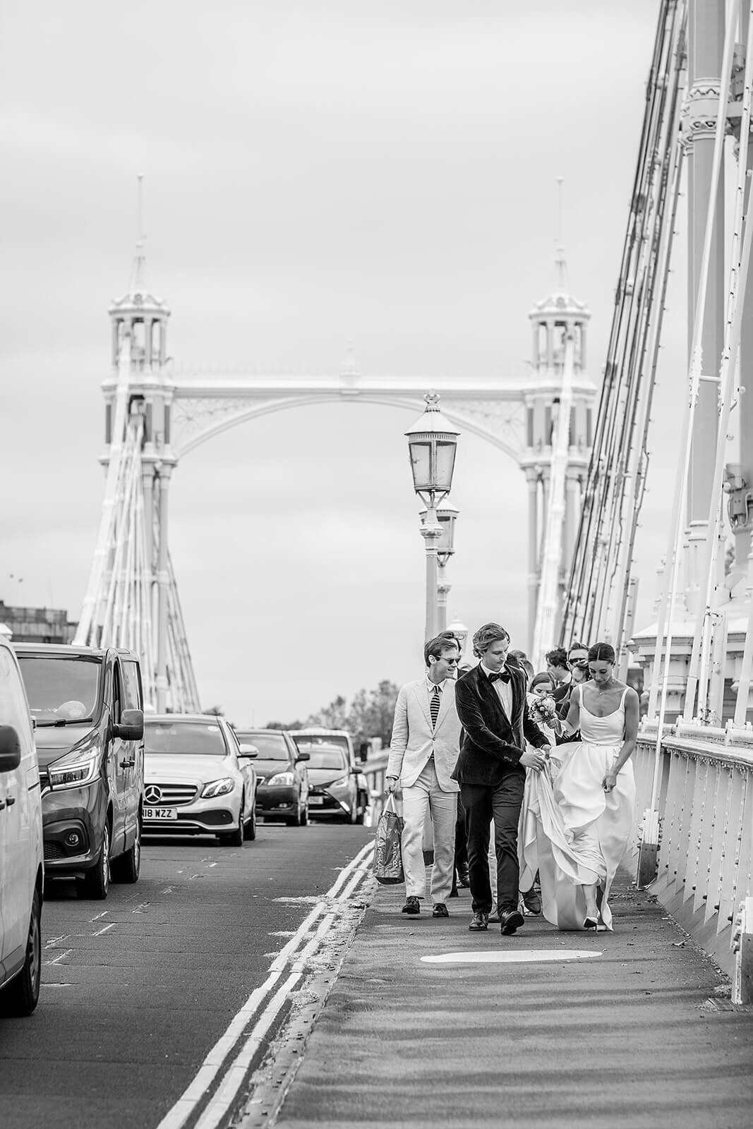 Bride, groom and bridal party walking over bridge
