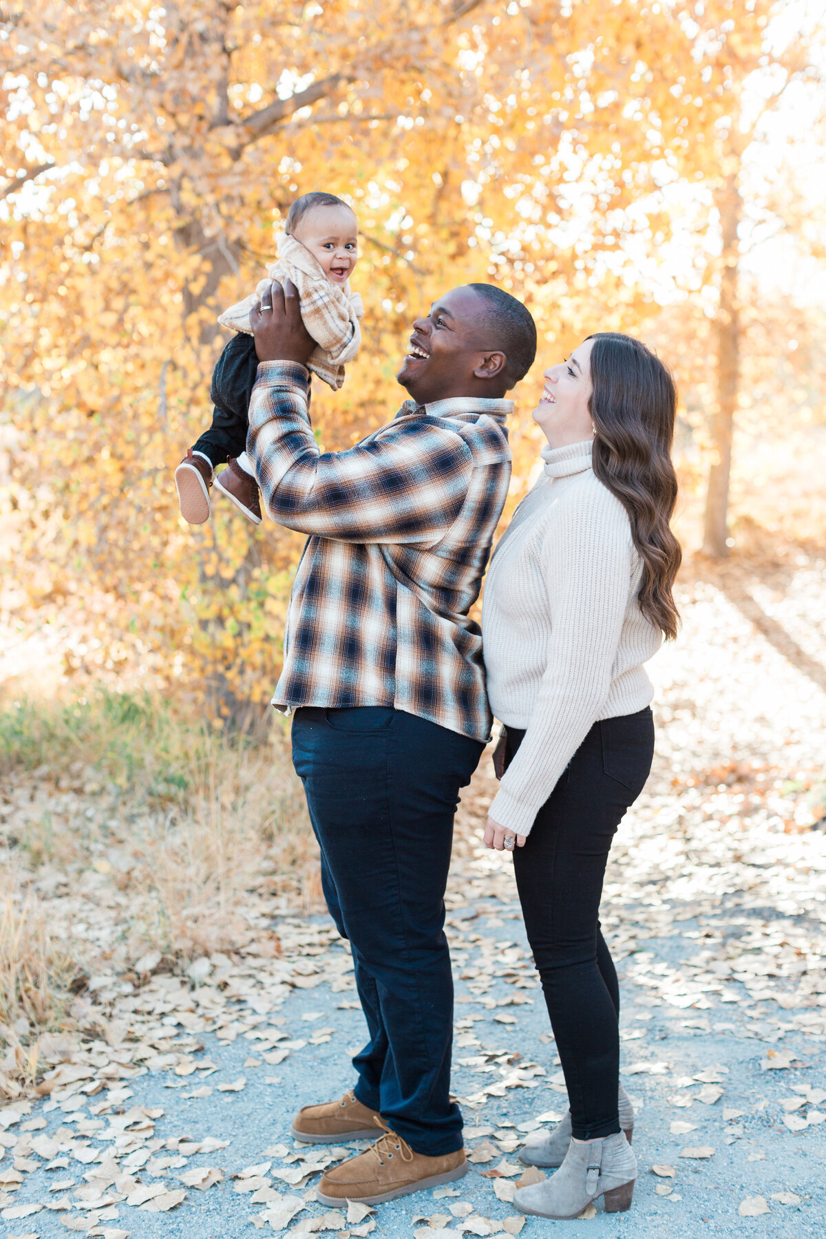 Parents with their baby next to fall leaves in Denver