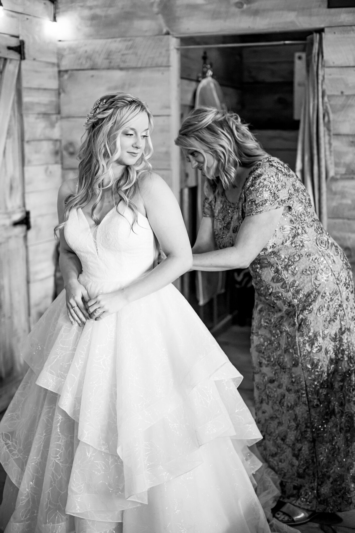 mom buttoning up daughter's wedding dress