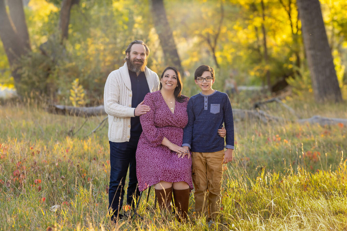 family of three standing together in a field