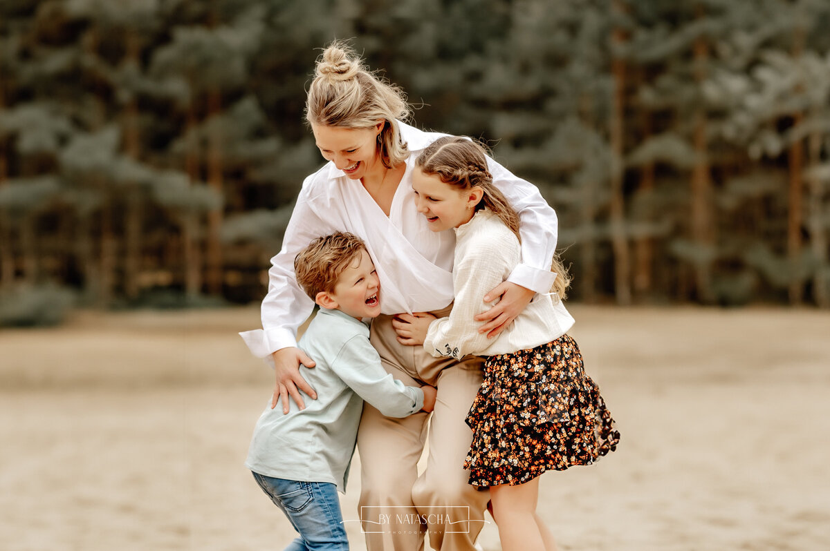 Mama met haar dochter en zoon die elkaar omhelzen in de duinen van Herperduin