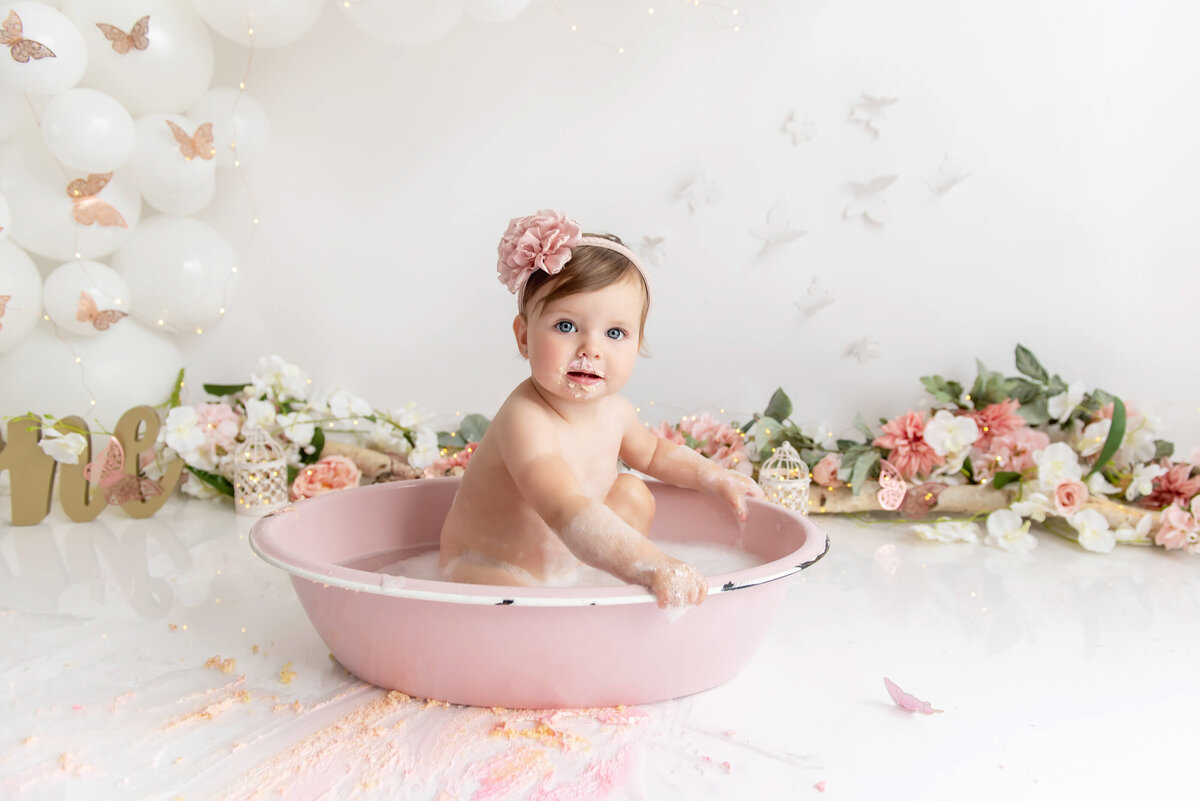 baby girl in a pink tub for her splash after the smash for her first birthday cake smash portrait session in Burlington, Ontario.