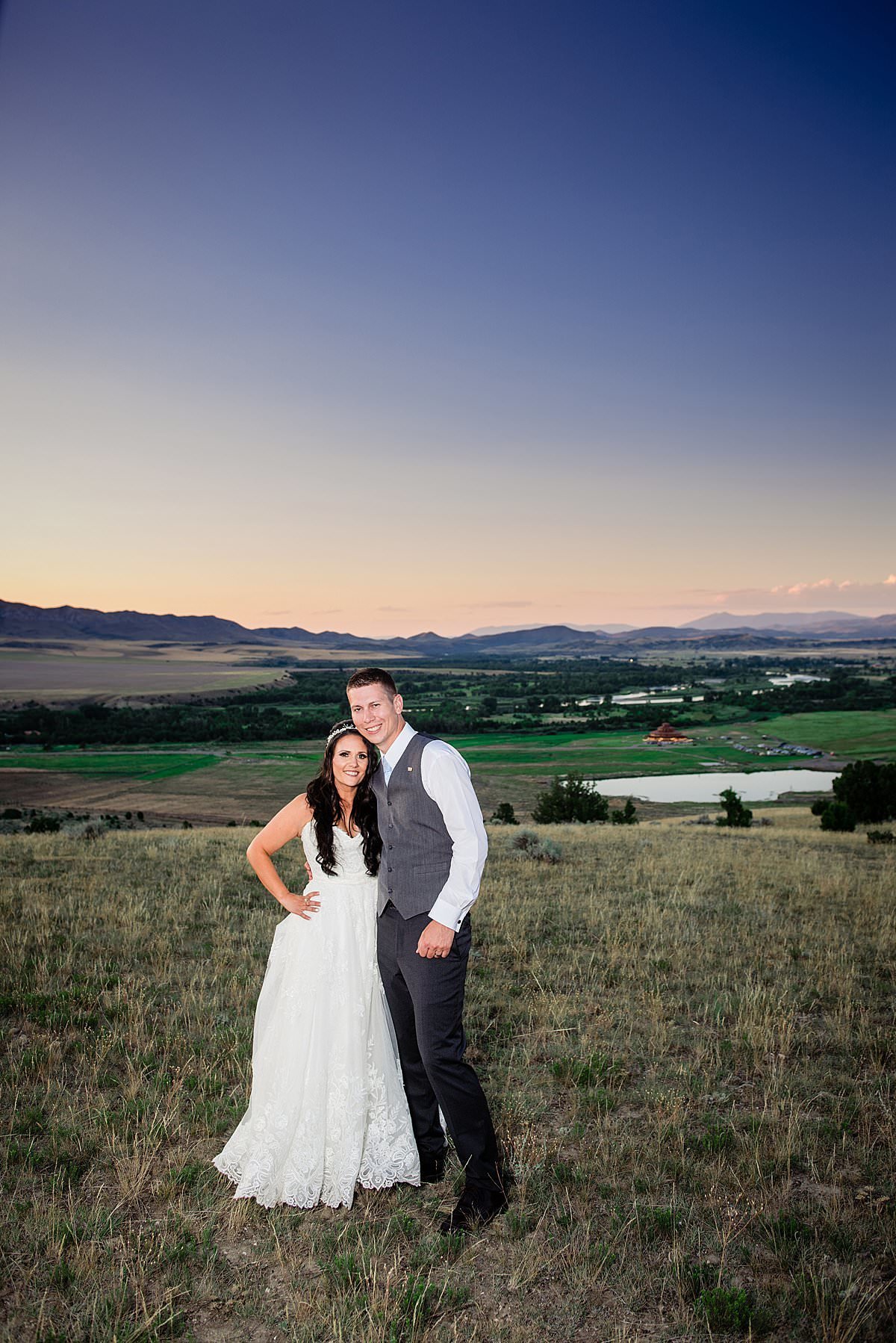 Bride and groom smiling at the camera as the big sky country sunset and overlooking Headwaters Ranch on their wedding day