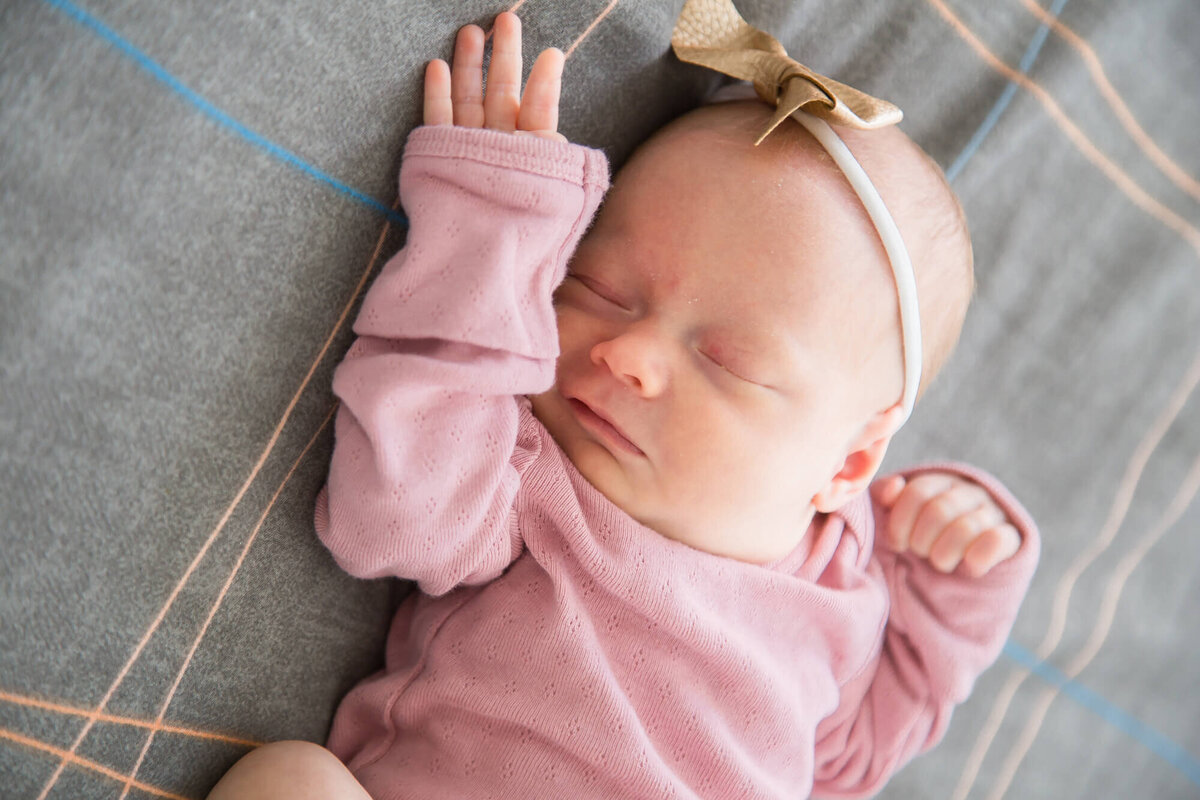 newborn baby girl  in pink stretching on a bed