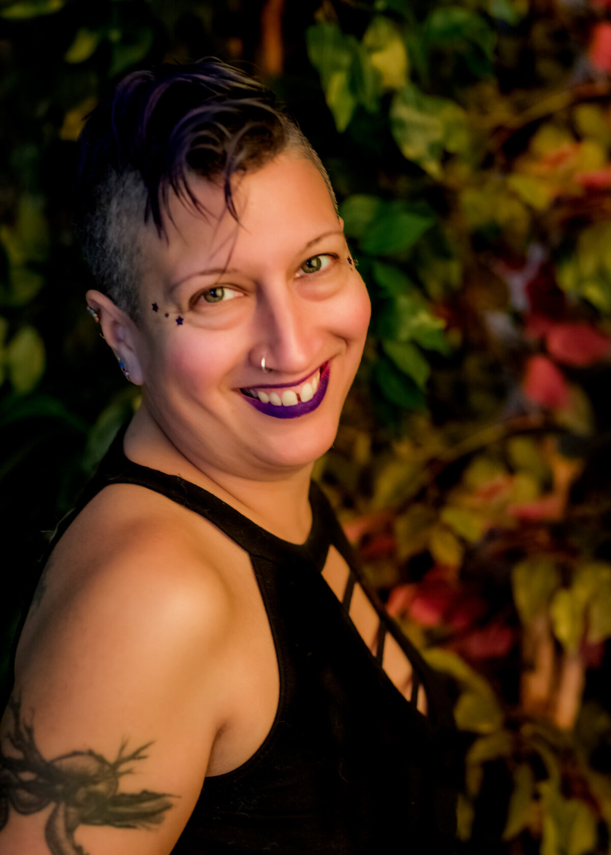 They/them headshot client wearing a black tank top, smiling at camera