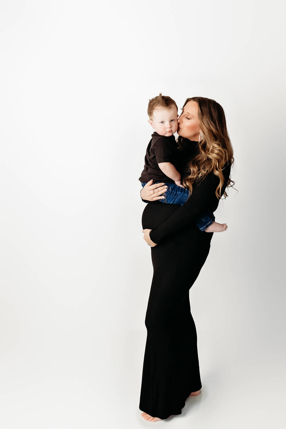 Pregnant mom with toddler boy studio session  against white backdrop