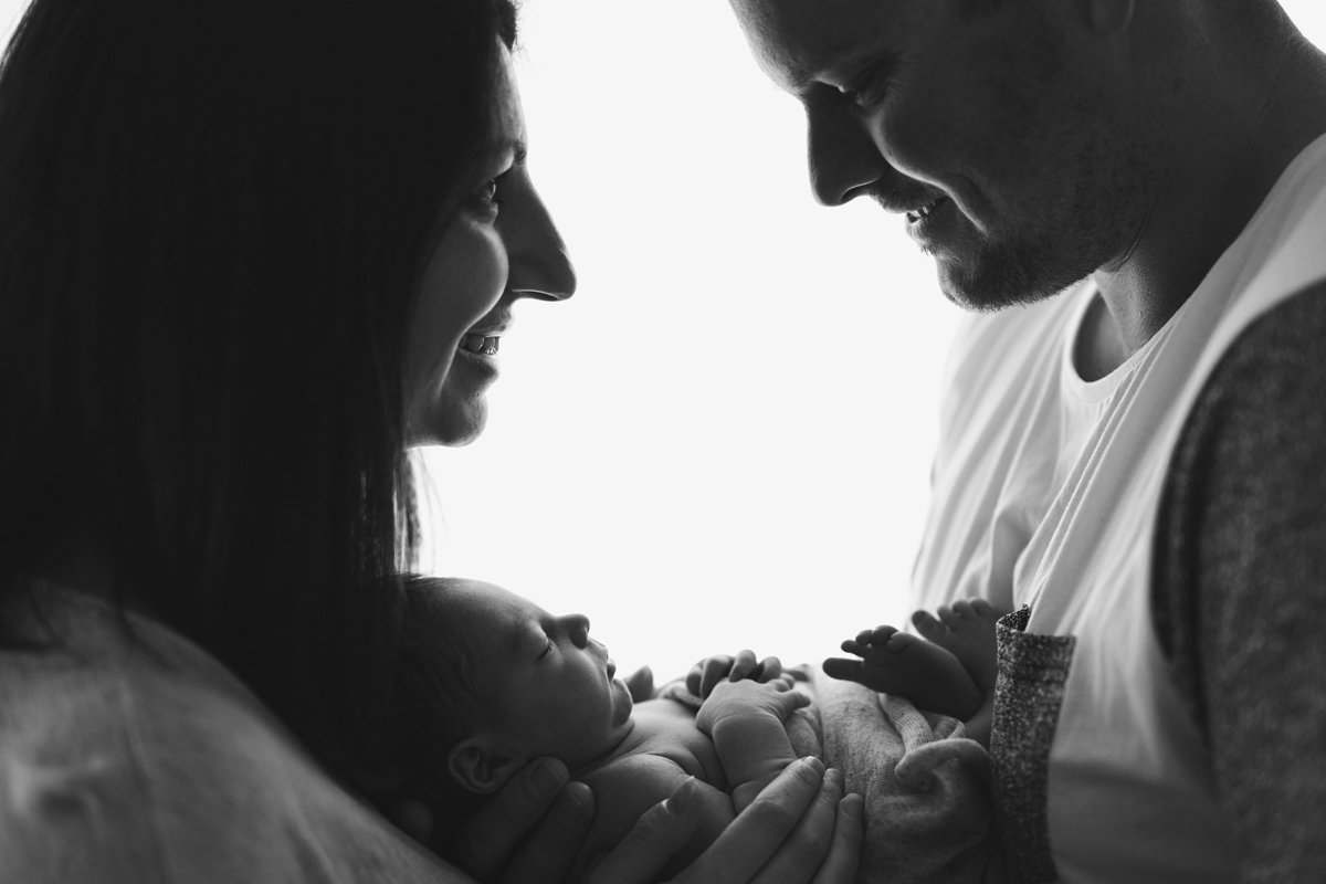 B&W of a couple holding a baby in the middle of them
