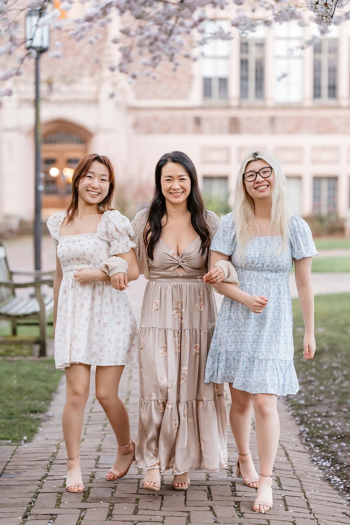Portrait of a mother with her daughters surrounded by soft pink cherry blossoms at the University of Washington in spring.