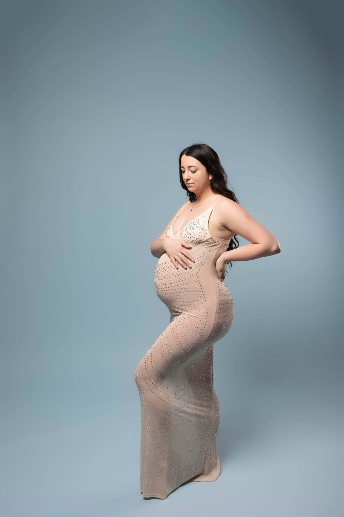 pregnant woman standing and looking at her belly in maternity session with reva davis photography