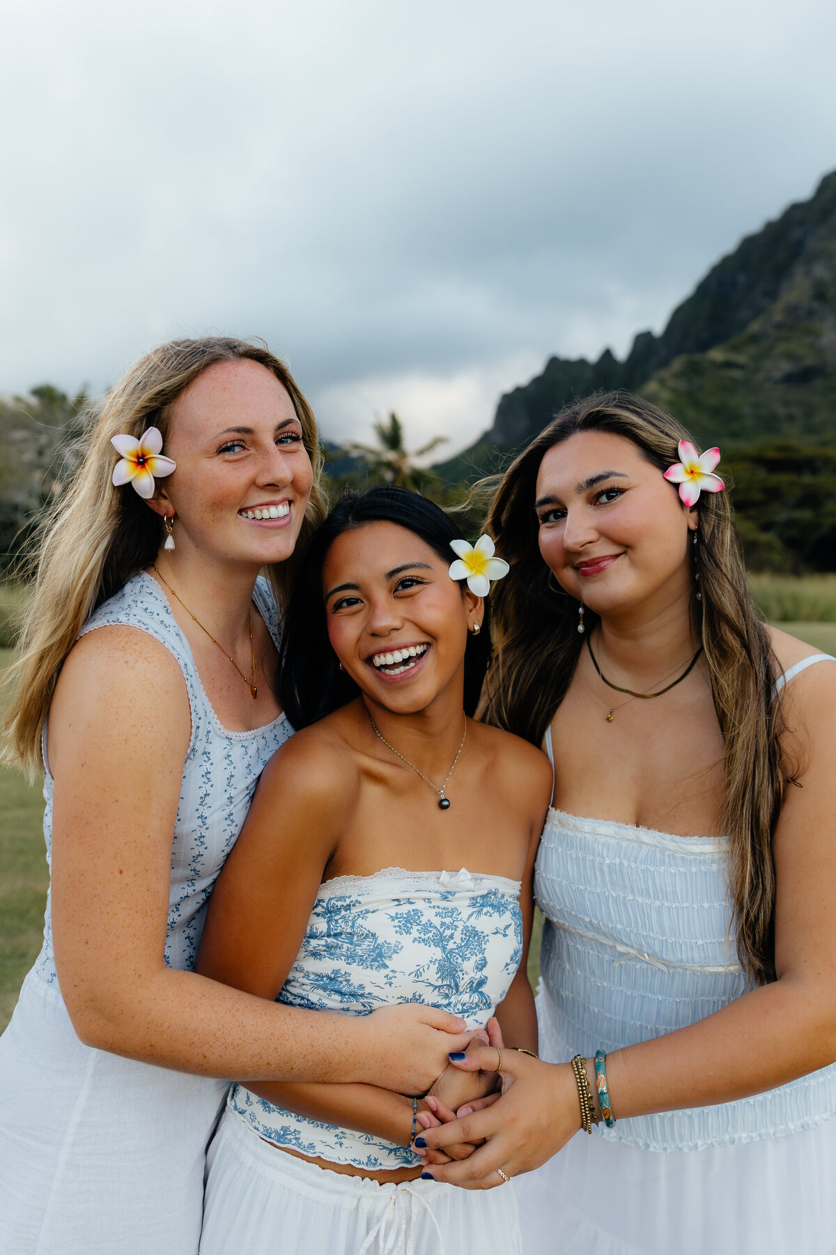 Three best friends hugging and laughing together at Kualoa Regional Park captured by Oahu Photographer Lexi Rae Photo