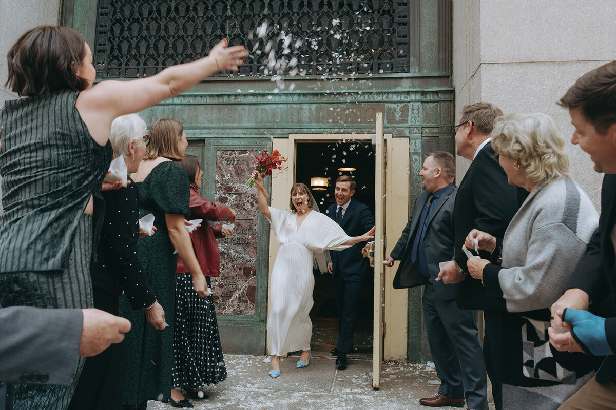family cheers for bride and groom coming outside after NY City Hall elopement shot by Elsie Goodman Photography | NYC Elopement Packages
