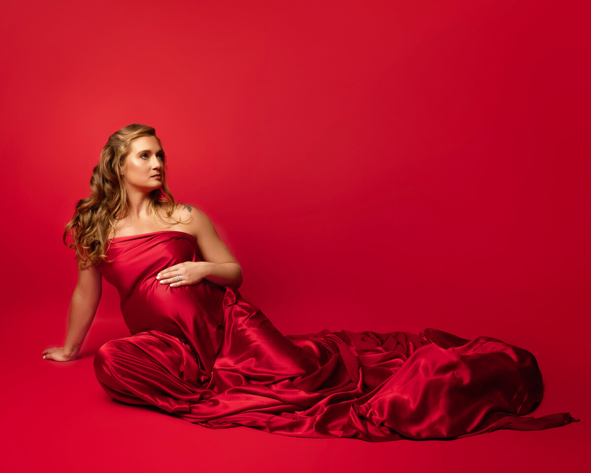 sitting pregnant woman blonde red fabric studio