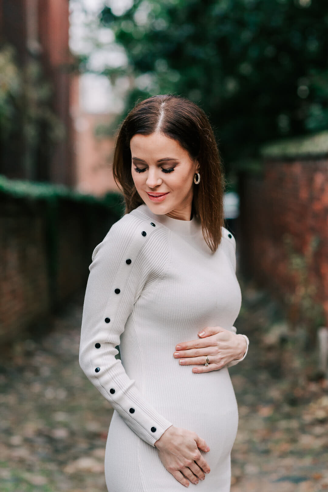 A woman in early pregnancy wearing white sweater dress in Alexandria VA