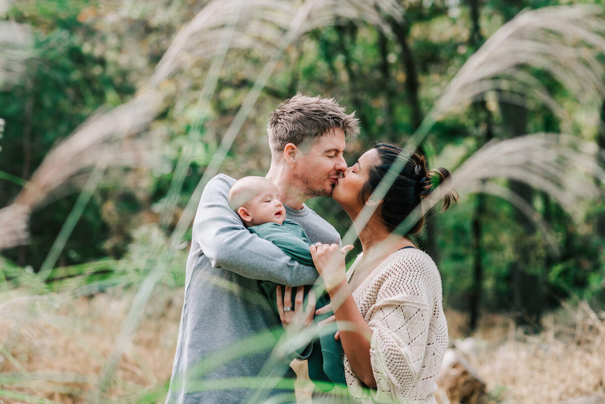 gorgeous parents kissing while holding their newborn son, by Denise Van a Northern VA newborn photographer