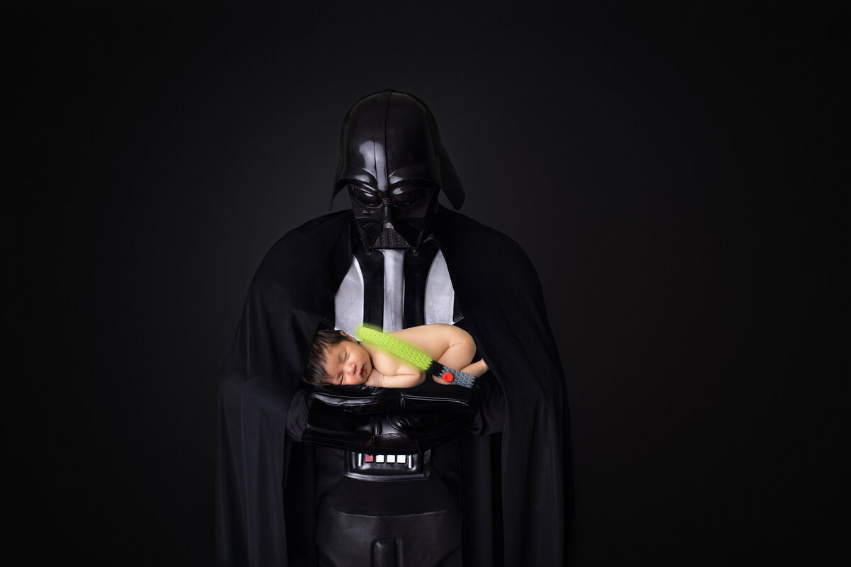 Newborn Photographer, a baby named "Luke" is held by Father dressed as Darth Vader