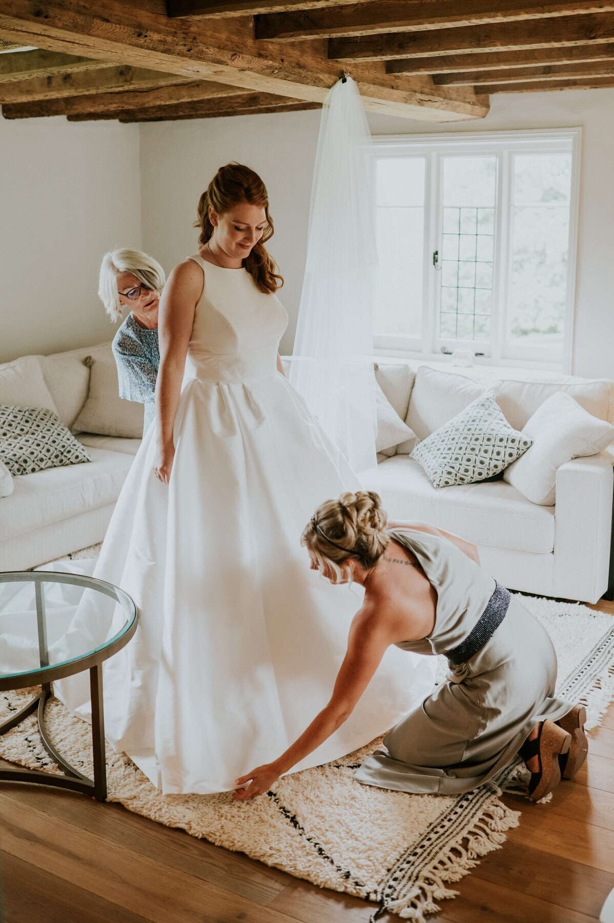 Bridesmaid and mother of the bride adjusting brides dress