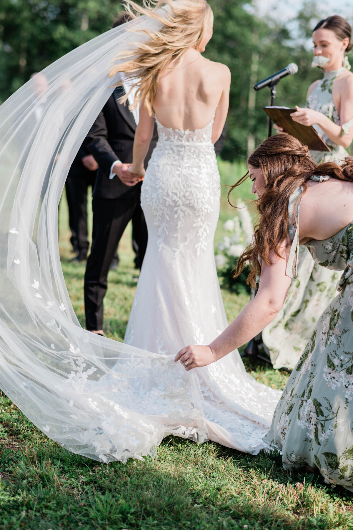 Bridesmaid adjusts wedding train and veil and the altar
