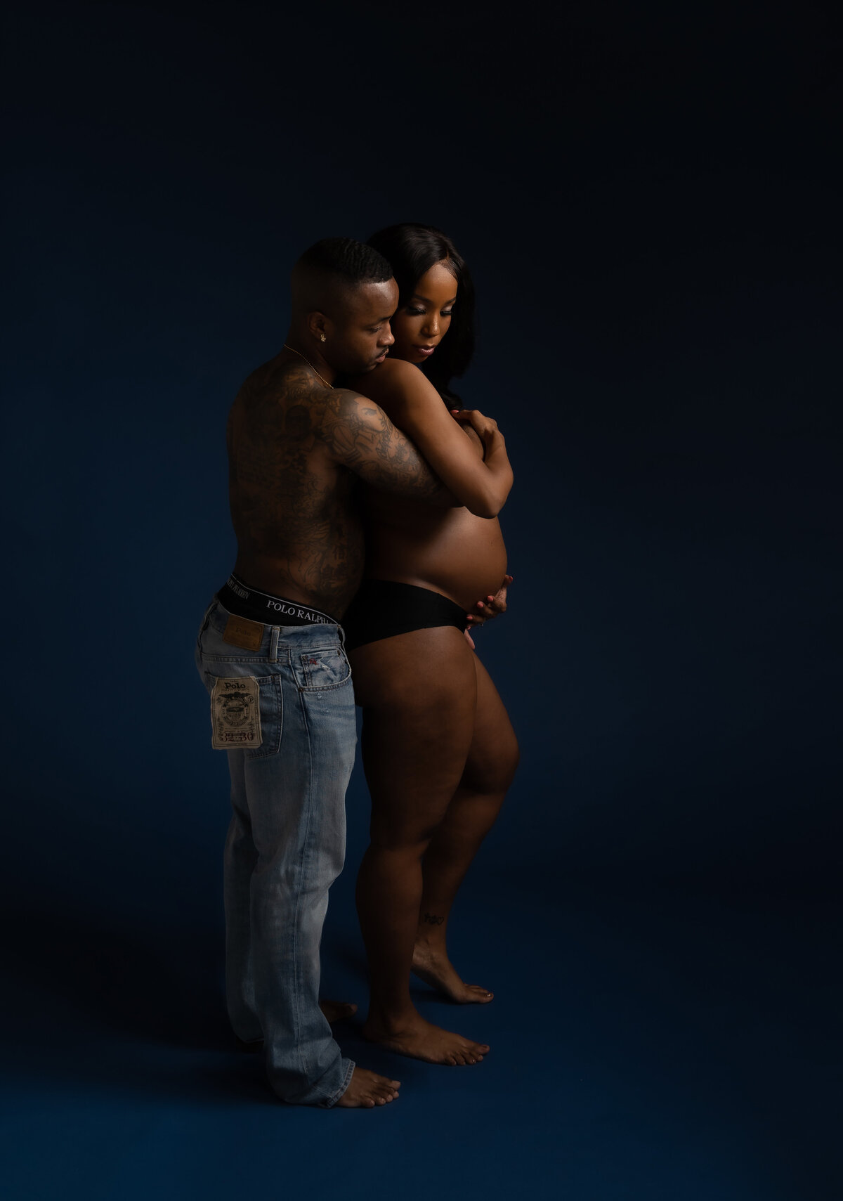 Black couple in blue jeans posing for maternity