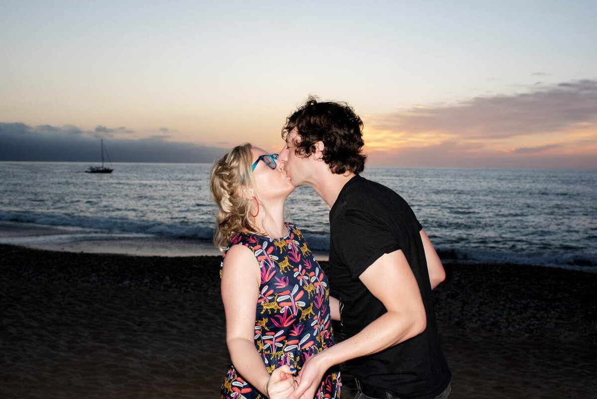 crystal genes kisses her boyfriend as the sun sets over the ocean in puerto vallarta