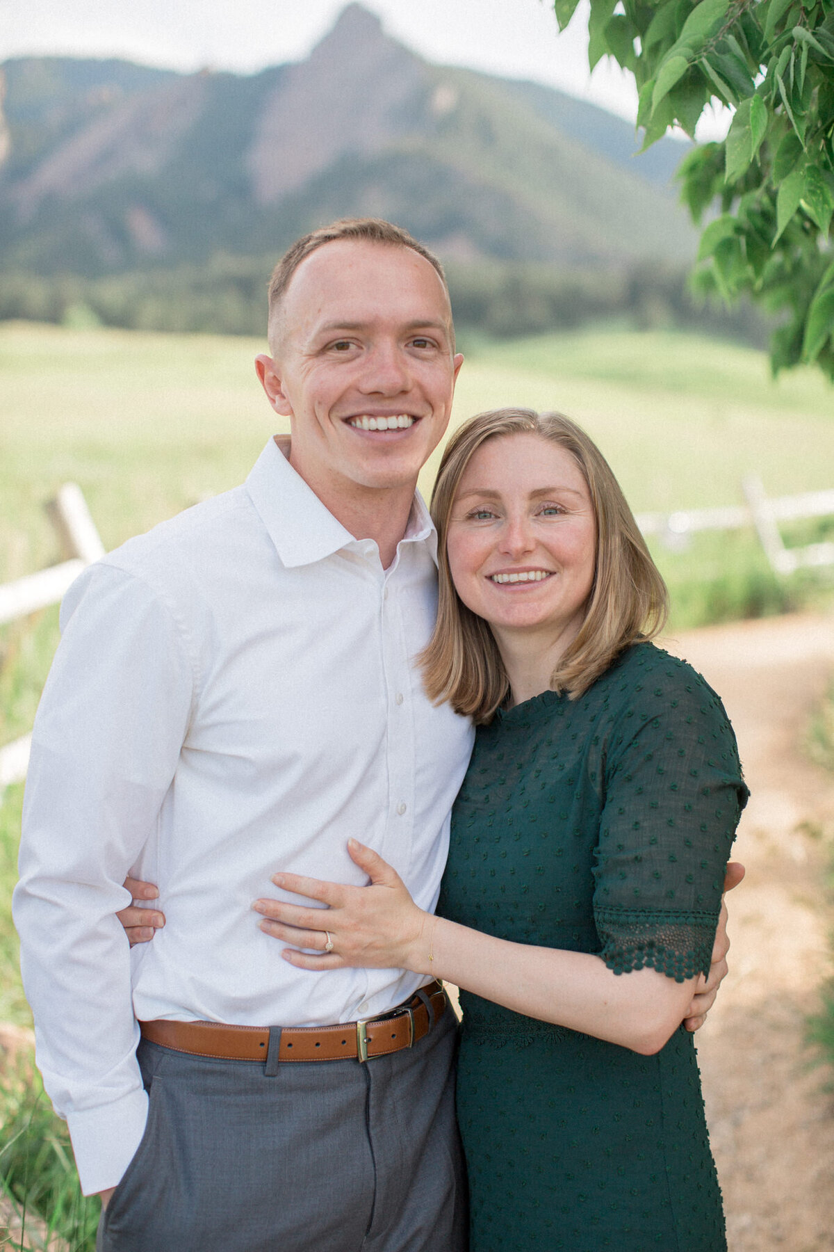A newly engaged man and woman pose for the camera and show of their engagement ring