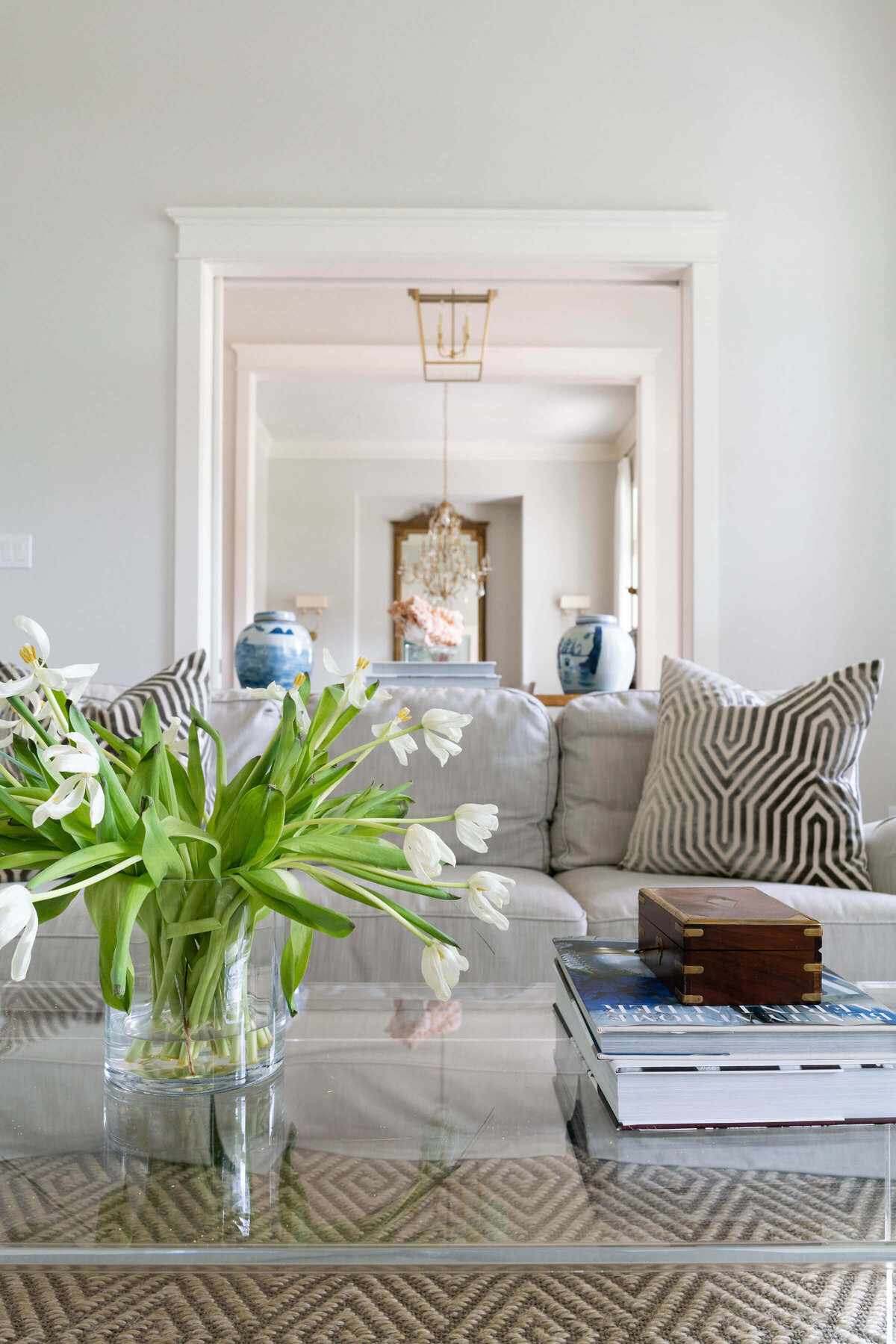 oyster creek studios heathcott fresh flowers on clear coffee table next to gray couch in living room