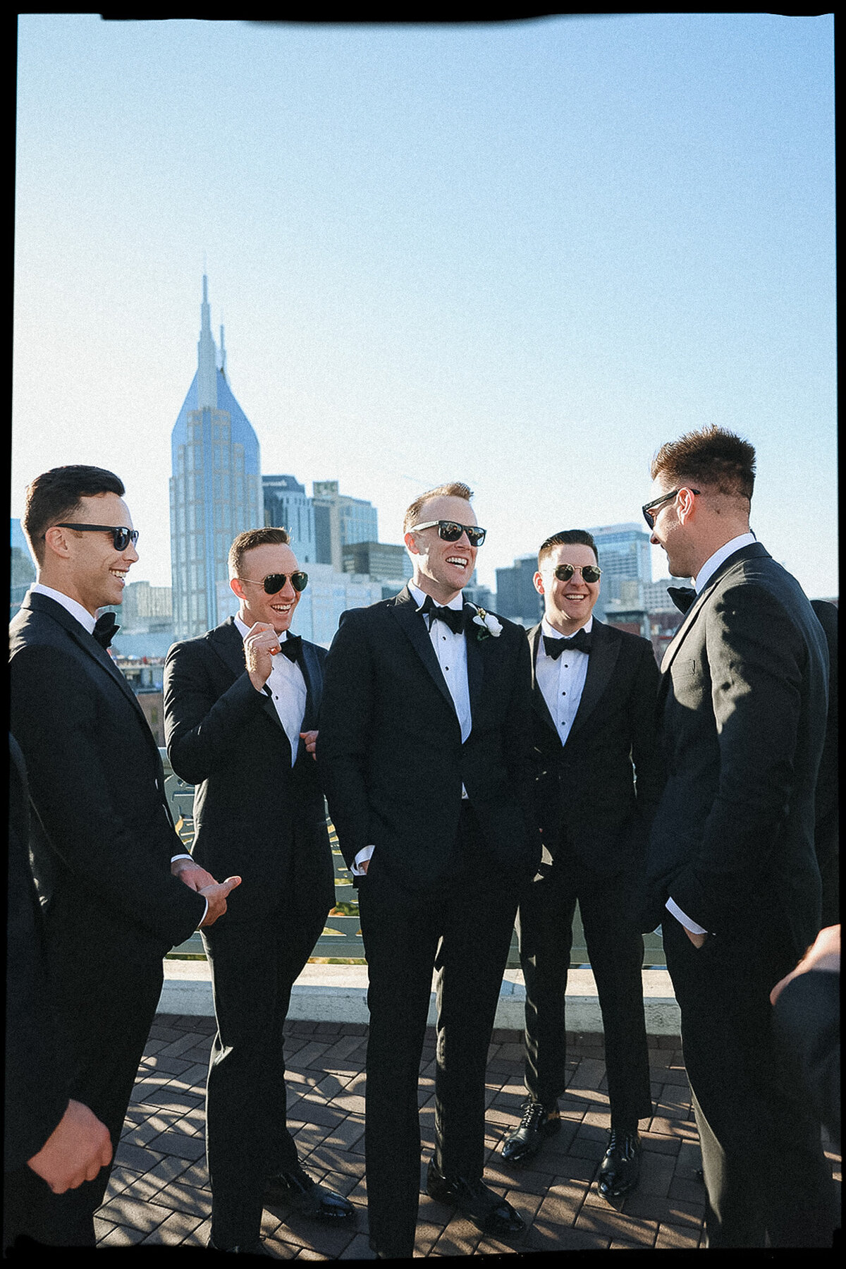 Groomsmen celebrate post-wedding day in black tuxes on the Pedestrian Bridge in downtown Nashville, TN.
