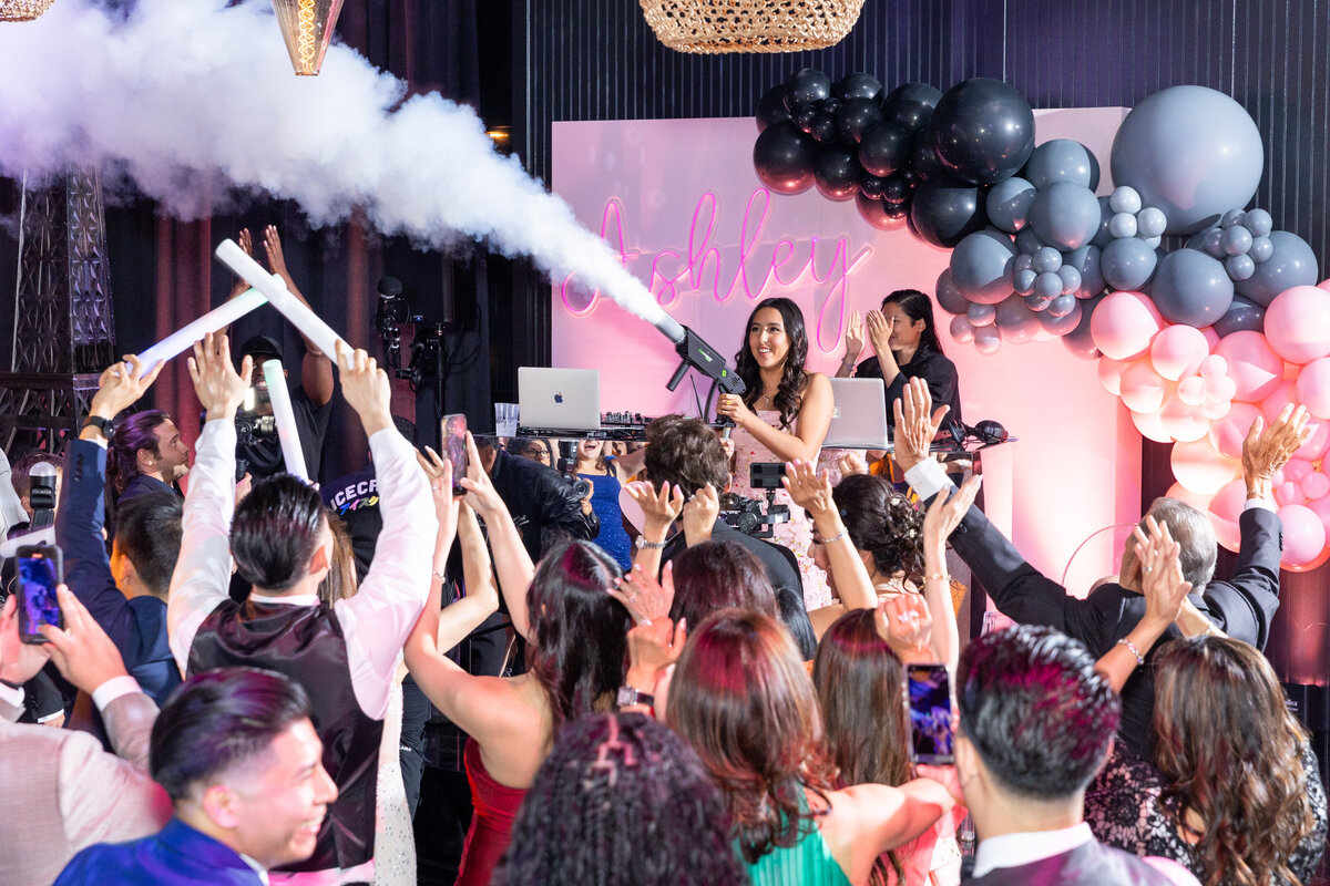 A girl holding out a smoke machine during a party