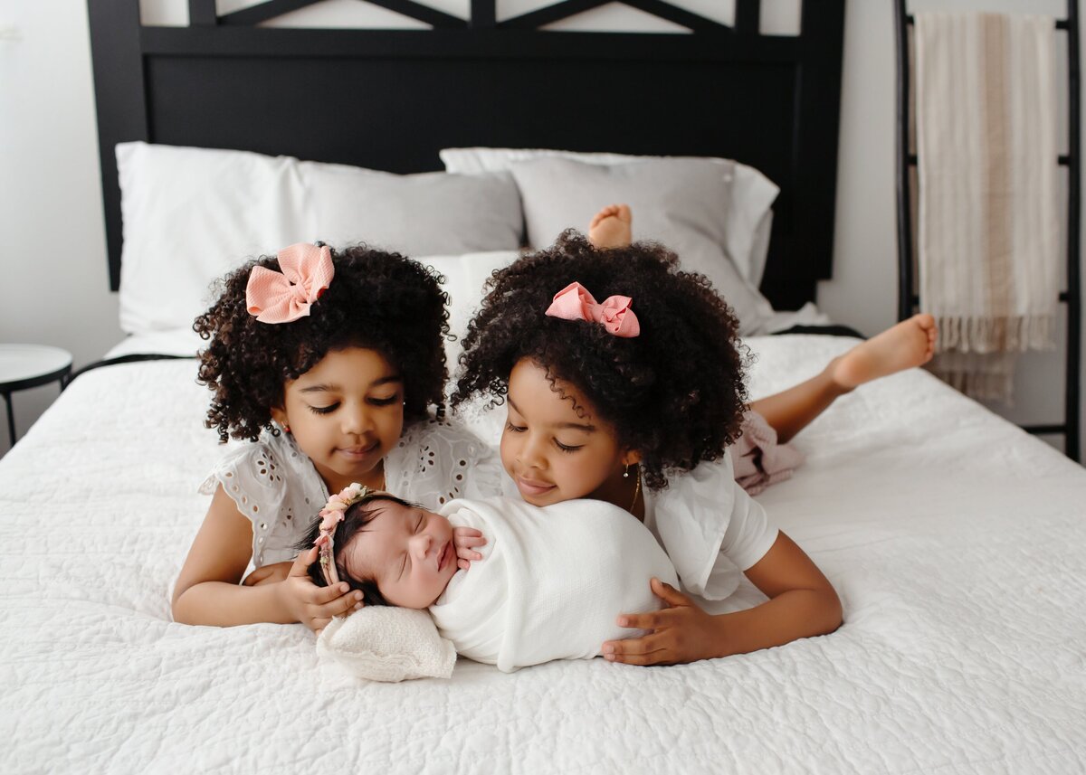 girls kissing their sisters while holding her