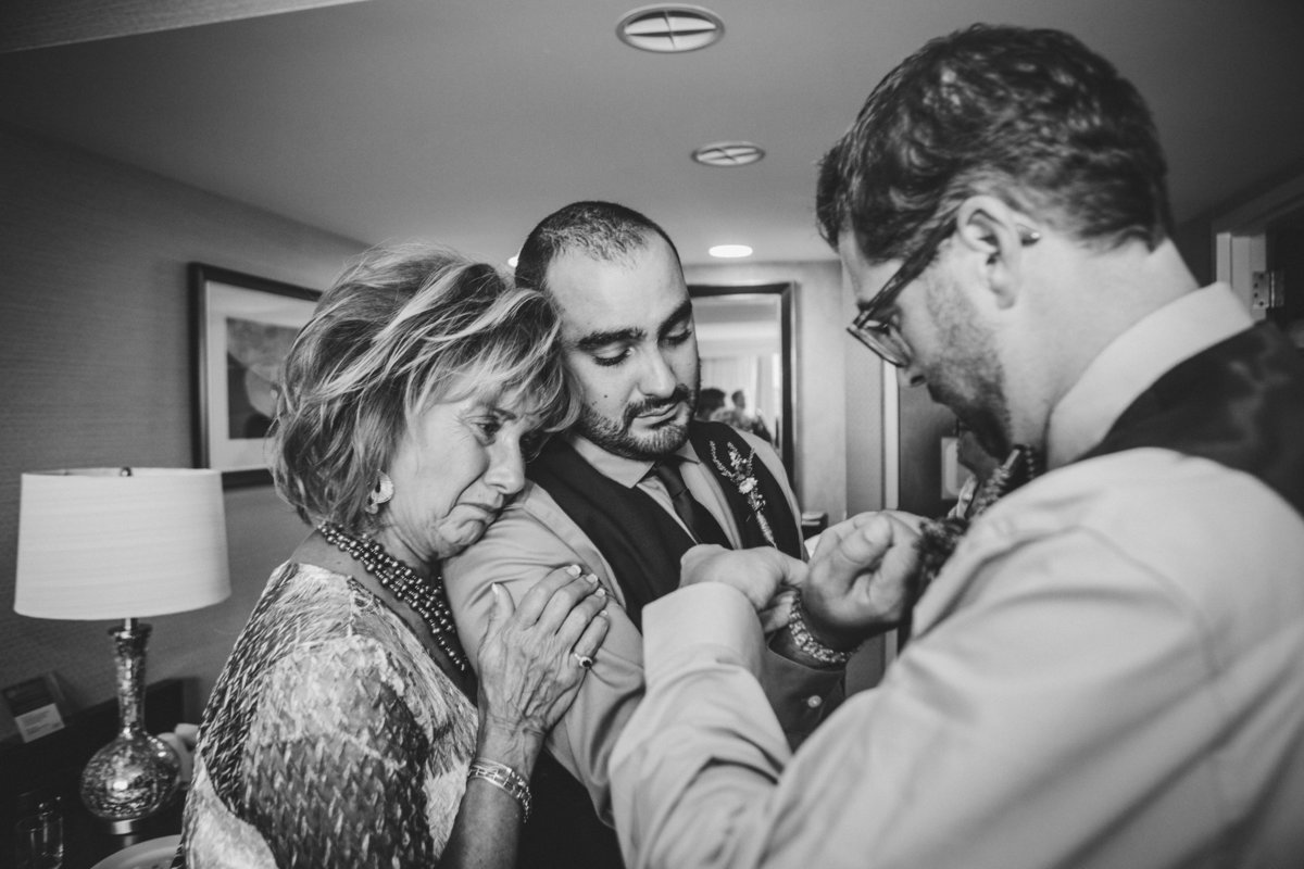 Brother putting watch on groom and mom crying