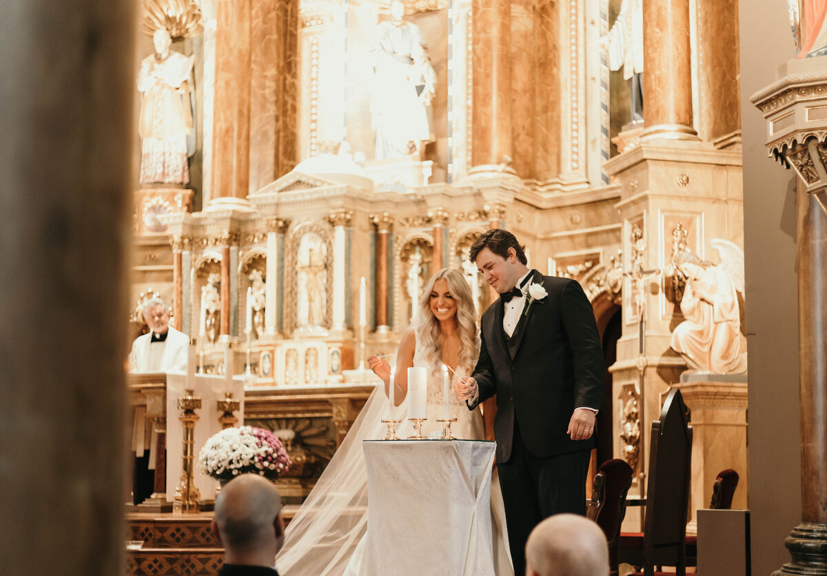 groom and bride at catholic church lighting unity candle