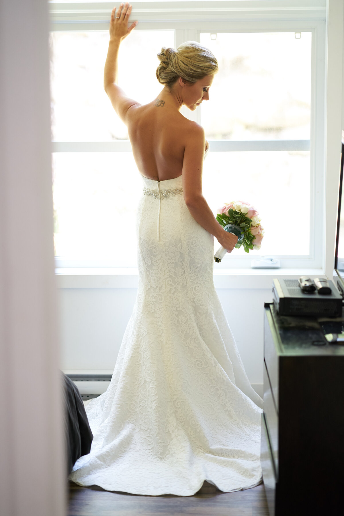 A bride, in her stunning wedding dress, raises her arms triumphantly while holding her bouquet. This image captures her joy and elegance, highlighting the beauty of her attire and the celebratory spirit of her special day.