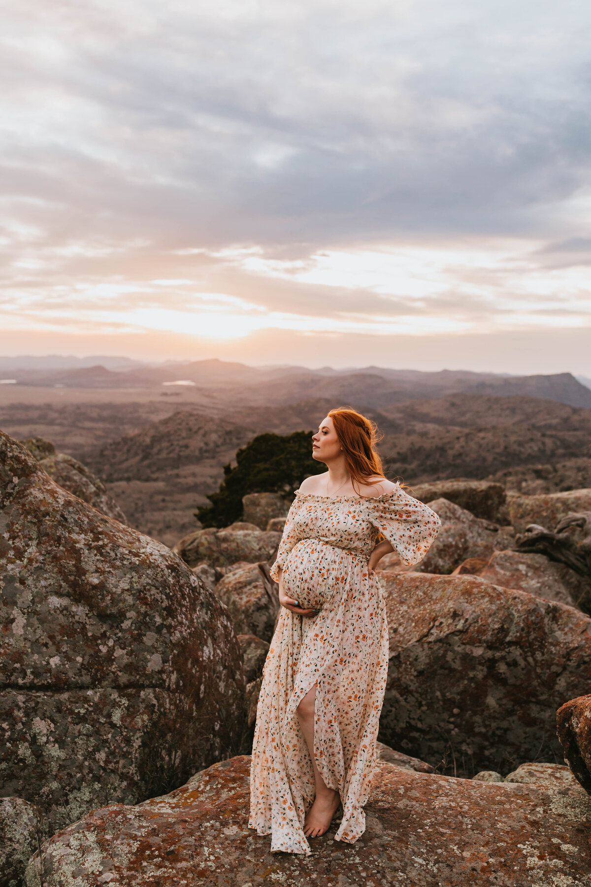 Redheaded pregnant mother in a floral flowy dress at wichita mountain wildlife refuge