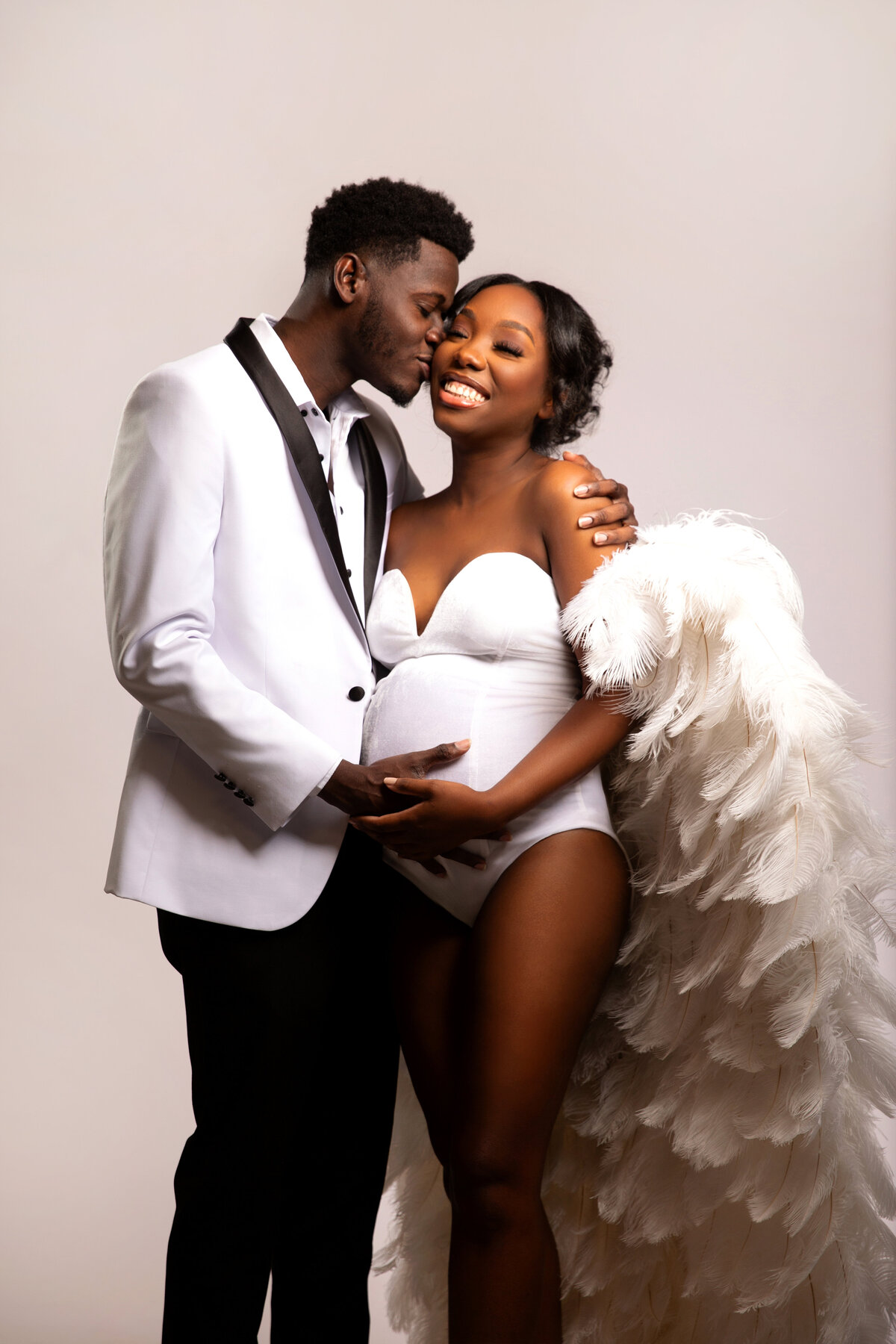 In love couple embracing while smiling holding baby bump.