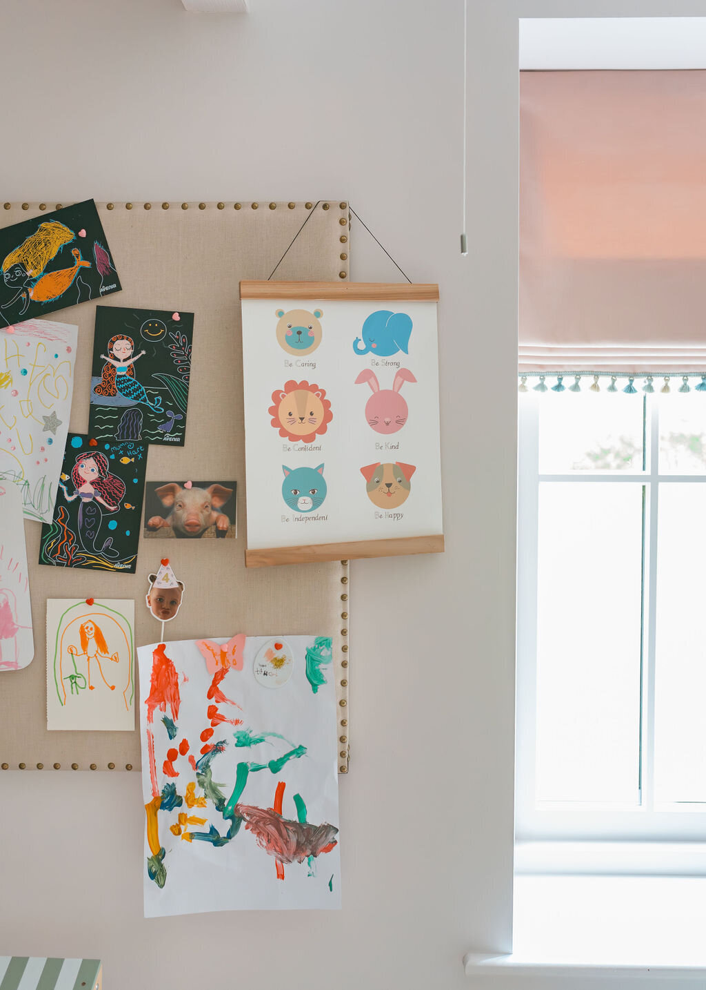 A board displaying children’s artwork in a cozy playroom.