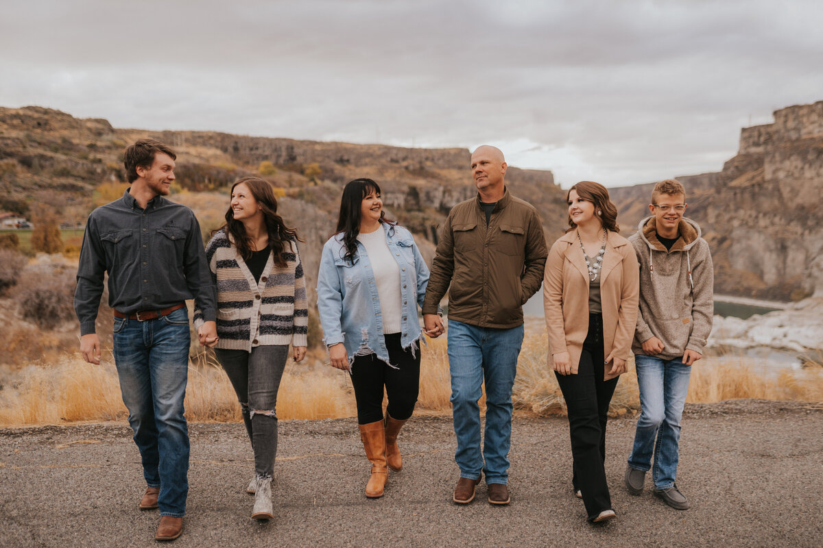 family holding hands while walking near Shoshone Falls, neutral family picture outfits