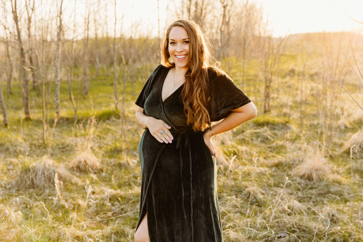 gorgeous expecting mom in a velvet dress embracing her bump for her maternity photo session