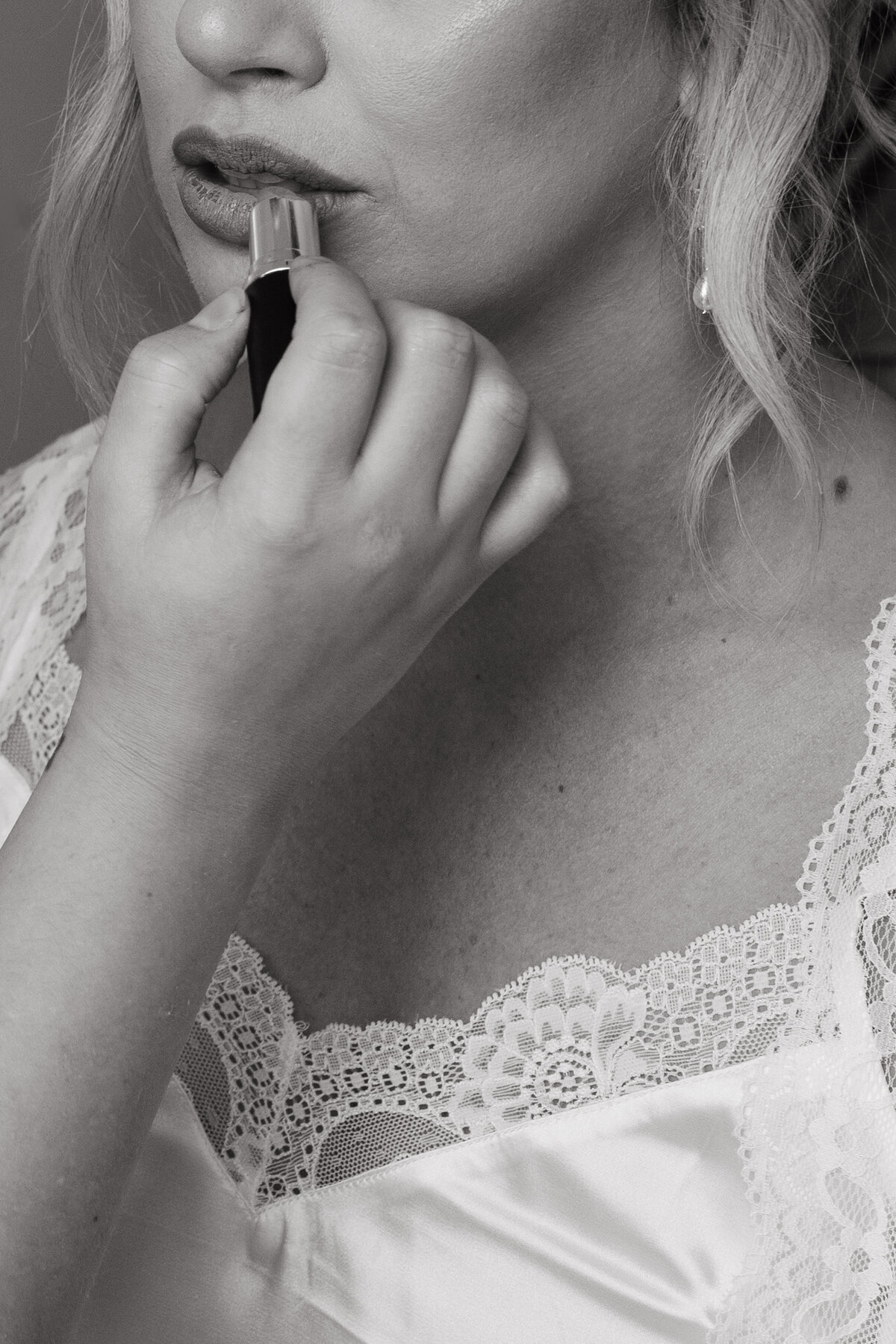 Black and white close-up of a bride applying lipstick before her ceremony — intimate getting-ready moment captured with cinematic elegance.