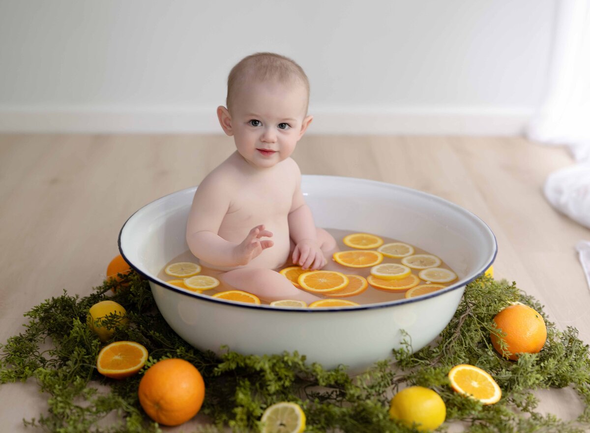 Baby boy sitting in basin full of oranges and lemons fruit bath. Baby photography near Atlanta, GA by Jenni Nikki Photography.