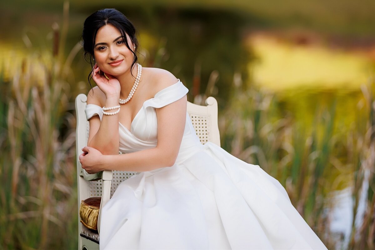 bride sitting in a chair in the grass smiling